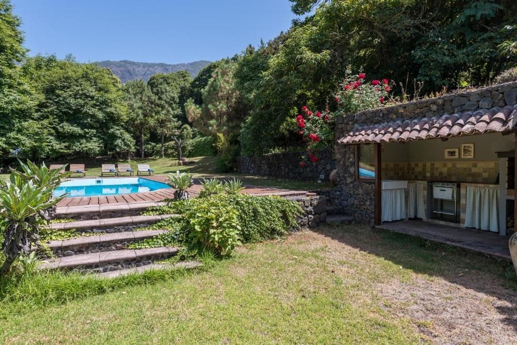 Piscina de la finca entre terrazas de piedra, jardín y buganvilla