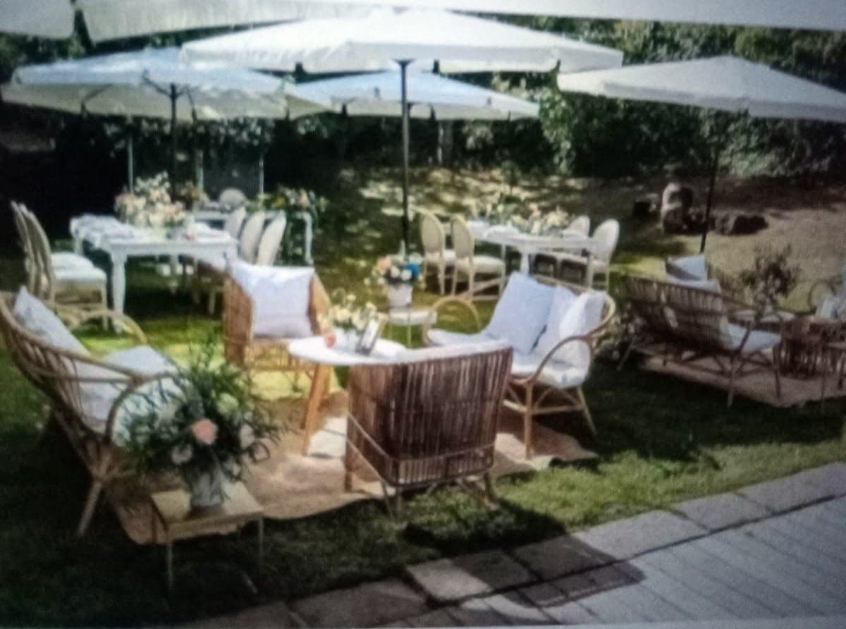 Salón al aire libre con sofás de mimbre y cojines blancos